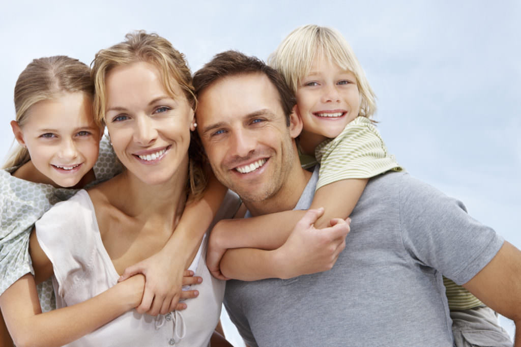 Portrait of a happy mature man and woman carrying kids on back